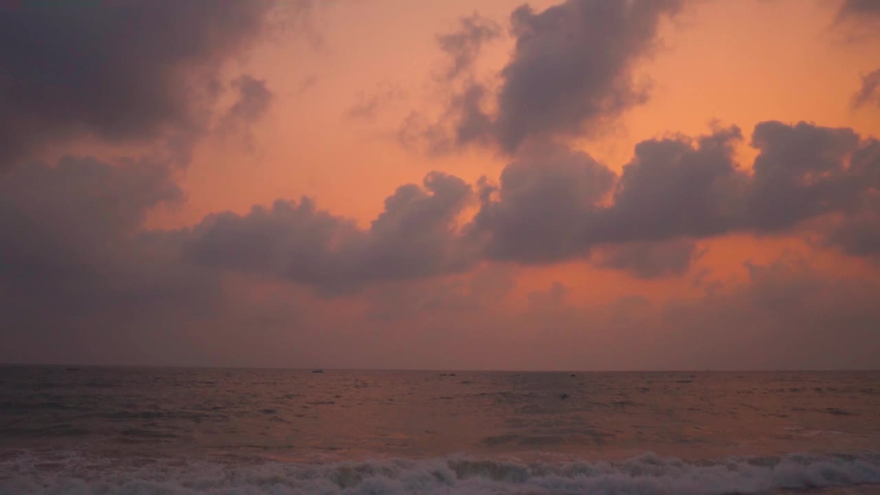 广角慢动作拍摄的海浪在科尔瓦海滩日落在果阿，印度。日落时海面上的云。美丽的海滩日落背景。在海滩度假的概念。视频素材