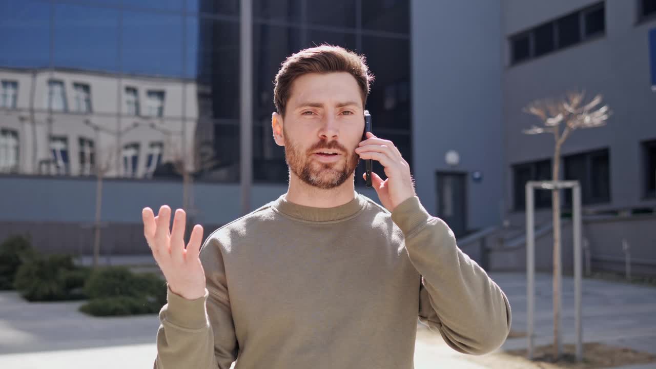 酷酷的时尚男人在户外用智能手机走路说话。大胡子男人在外面打电话。视频素材