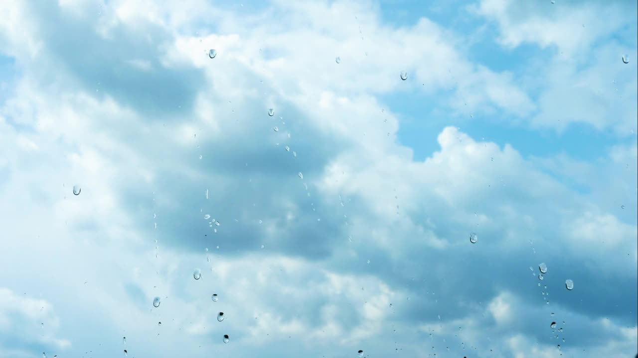 时间流逝期间蓬松的白云雨滴顺着玻璃流下，雨点落在窗外视频素材