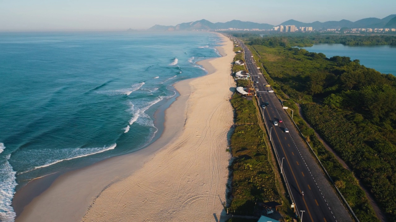 航拍Reserva海滩，Marapendi泻湖和Lucio Costa大道上的汽车交通。Barra da Tijuca和Recreio，在巴西的里约热内卢。日出。阳光明媚的一天。无人驾驶飞机。普拉达珍藏视频素材