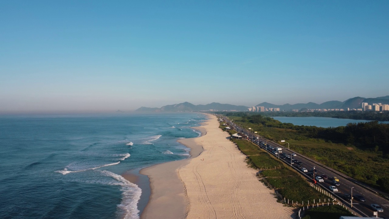 航拍Reserva海滩，Marapendi泻湖和Lucio Costa大道上的汽车交通。Barra da Tijuca和Recreio，在巴西的里约热内卢。日出。阳光明媚的一天。无人驾驶飞机。普拉达珍藏视频素材