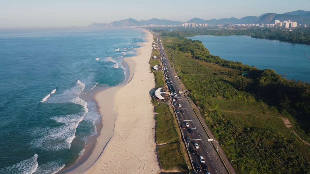 航拍Reserva海滩，Marapendi泻湖和Lucio Costa大道上的汽车交通。Barra da Tijuca和Recreio，在巴西的里约热内卢。日出。阳光明媚的一天。无人驾驶飞机。普拉达珍藏视频素材