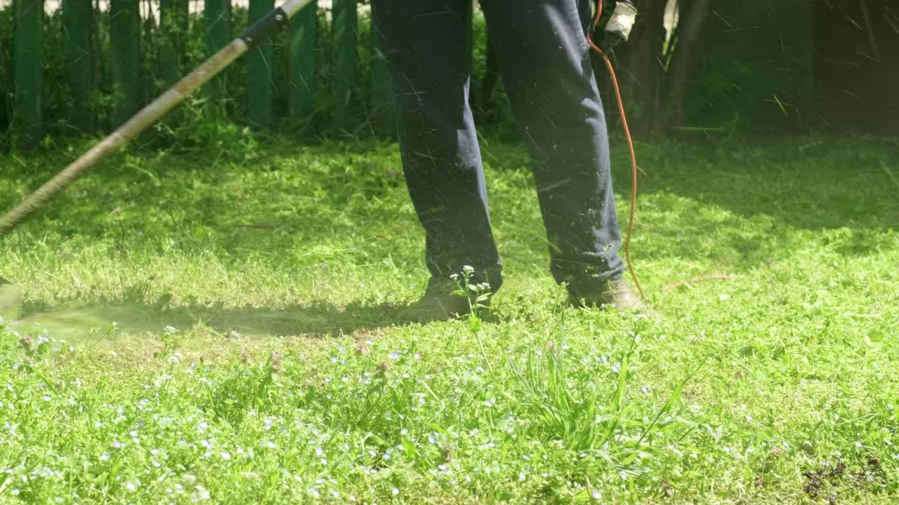 男人在花园里用手电动割草机割草视频素材
