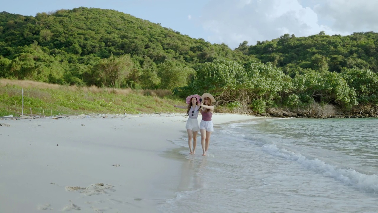 两名亚洲女性博客作者正在用动作相机拍摄在海上岛屿的海滩旅行，自由的概念、旅行、冒险的照片，并在社交媒体上向朋友们炫耀视频素材