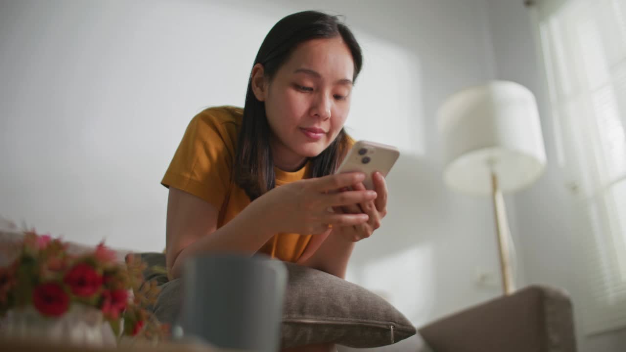 亚洲年轻女子看着智能手机和微笑视频素材