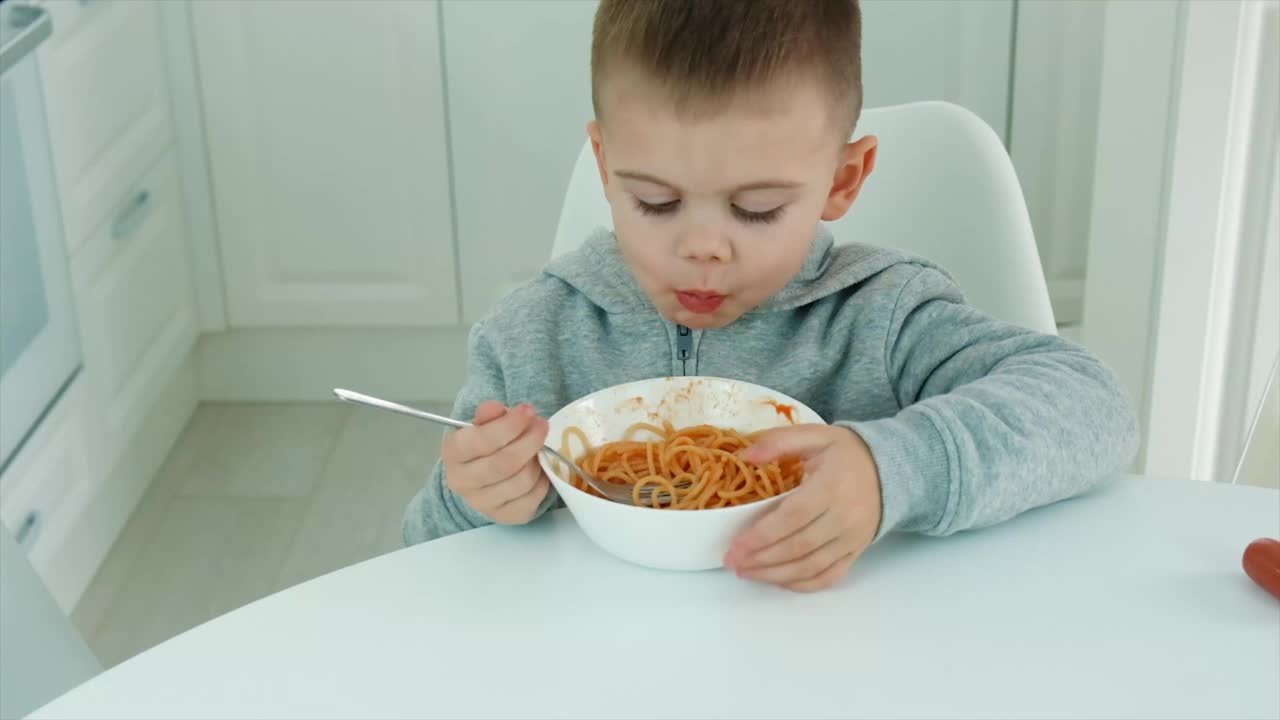 孩子在厨房里吃意大利面。有选择性的重点。视频素材