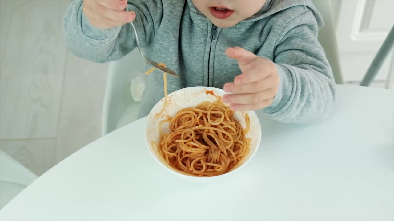 孩子在厨房里吃意大利面。有选择性的重点。视频素材