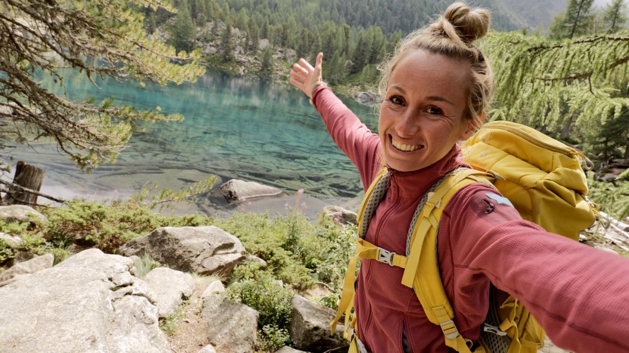 年轻女子在美丽的高山湖泊徒步旅行时自拍视频素材