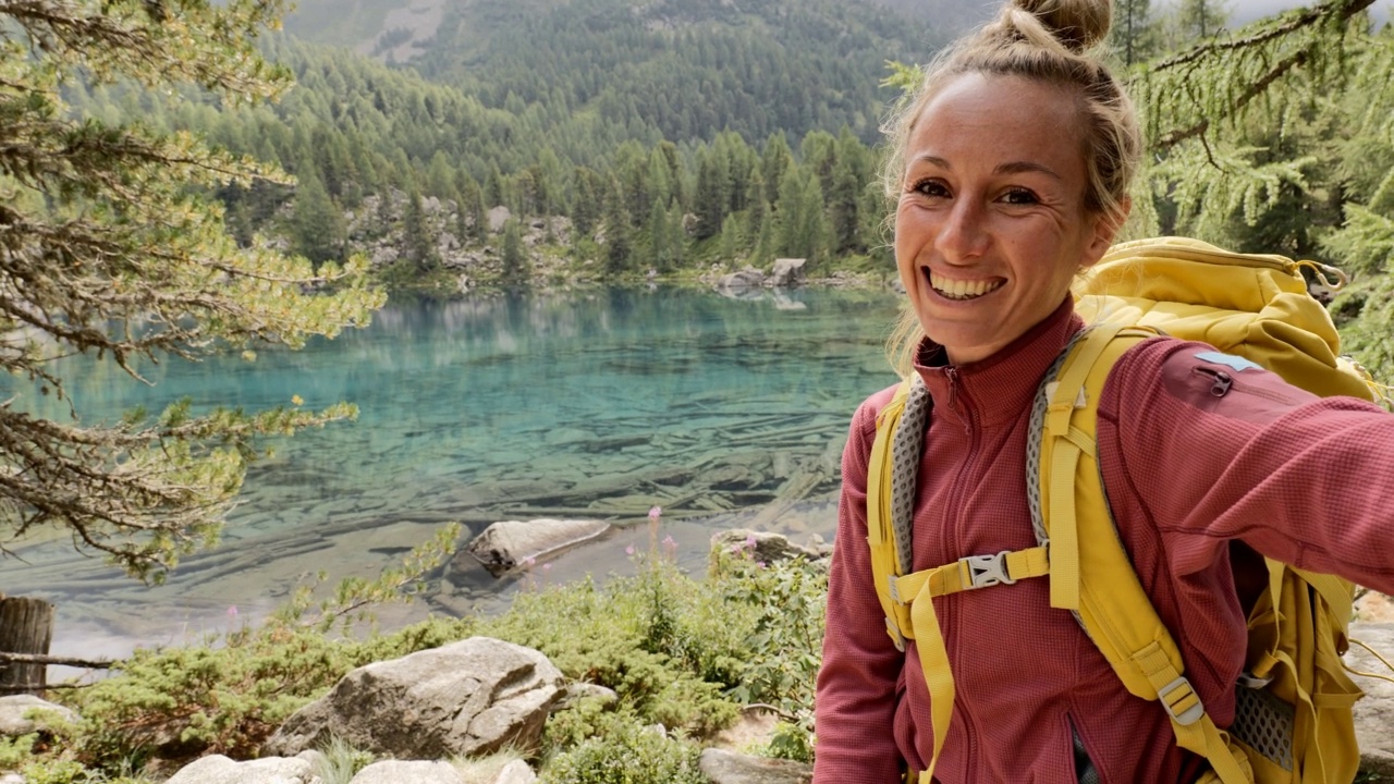 年轻女子在美丽的高山湖泊徒步旅行时自拍视频素材