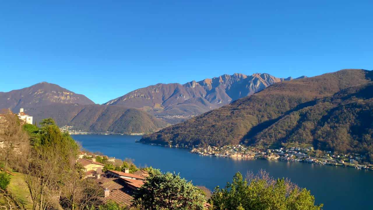 阳光明媚的日子里卢加诺湖与村庄的山景视频素材