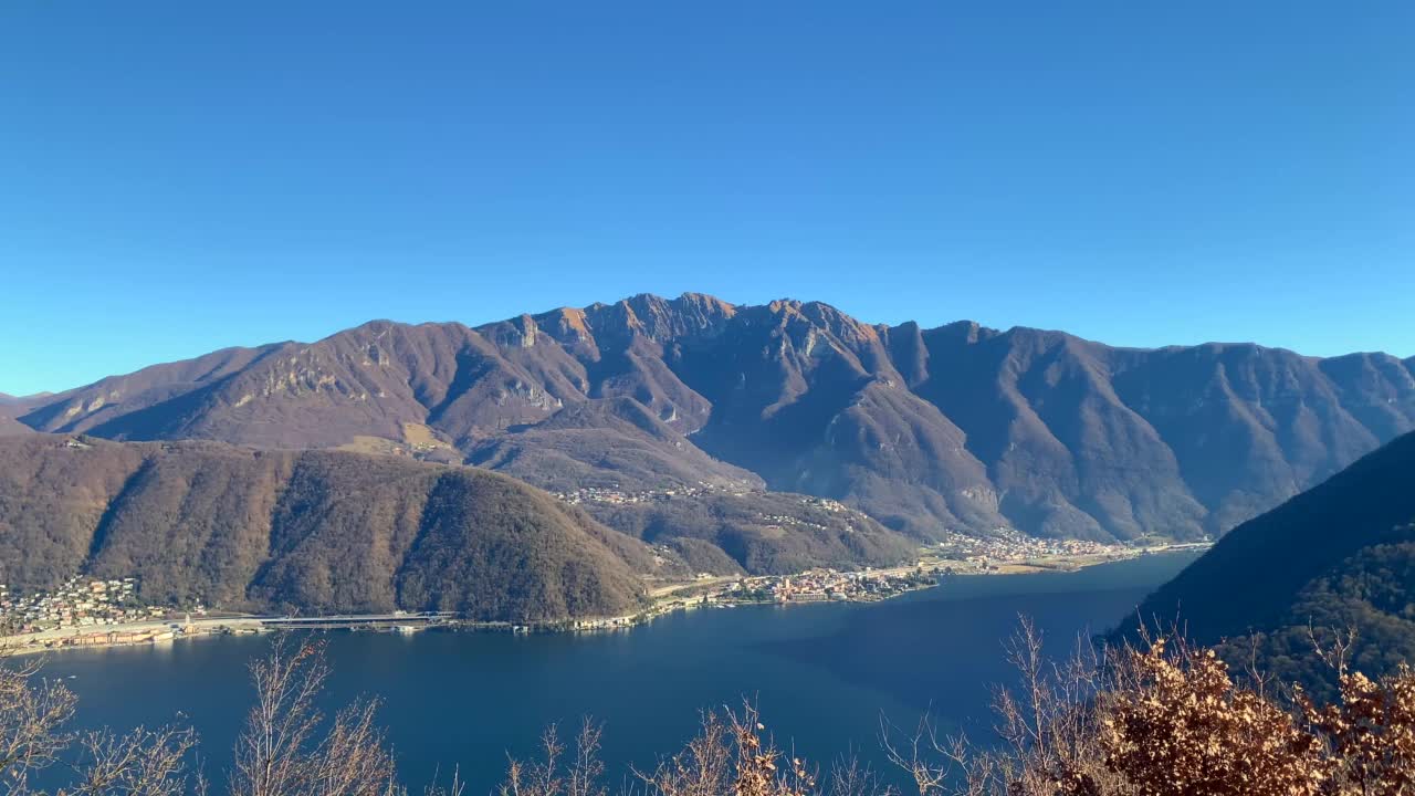 阳光明媚的日子里，卢加诺湖上的蒙特吉诺索山景与村庄视频素材