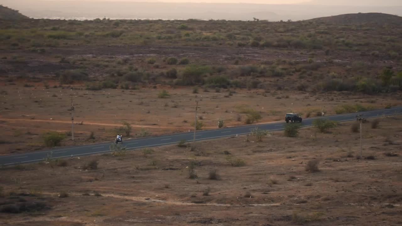 在印度古吉拉特邦库奇沙漠地带的公路上，车辆驶过。荒芜的道路通向库奇沙漠的荒野。视频素材