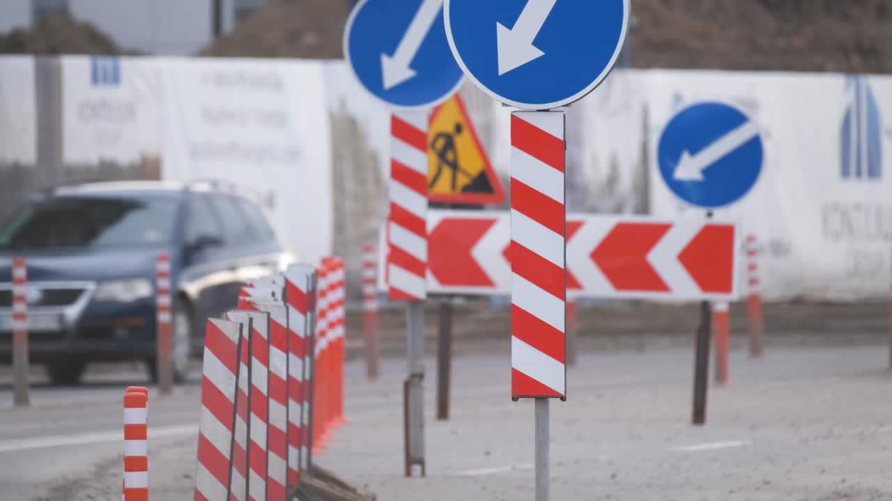 道路工程警告交通标志的建设工作在城市街道和缓慢移动的汽车视频素材