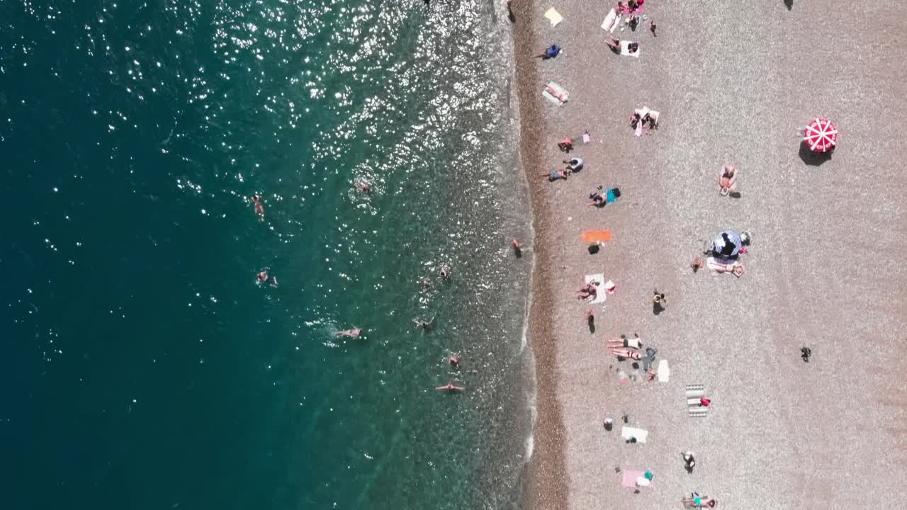 宽阔的海滩，有许多日光浴床和雨伞。人们在炎热的夏天躺在沙滩上。暑假的概念。休闲娱乐活动。游客们在阳光下晒日光浴，放松和放松视频素材