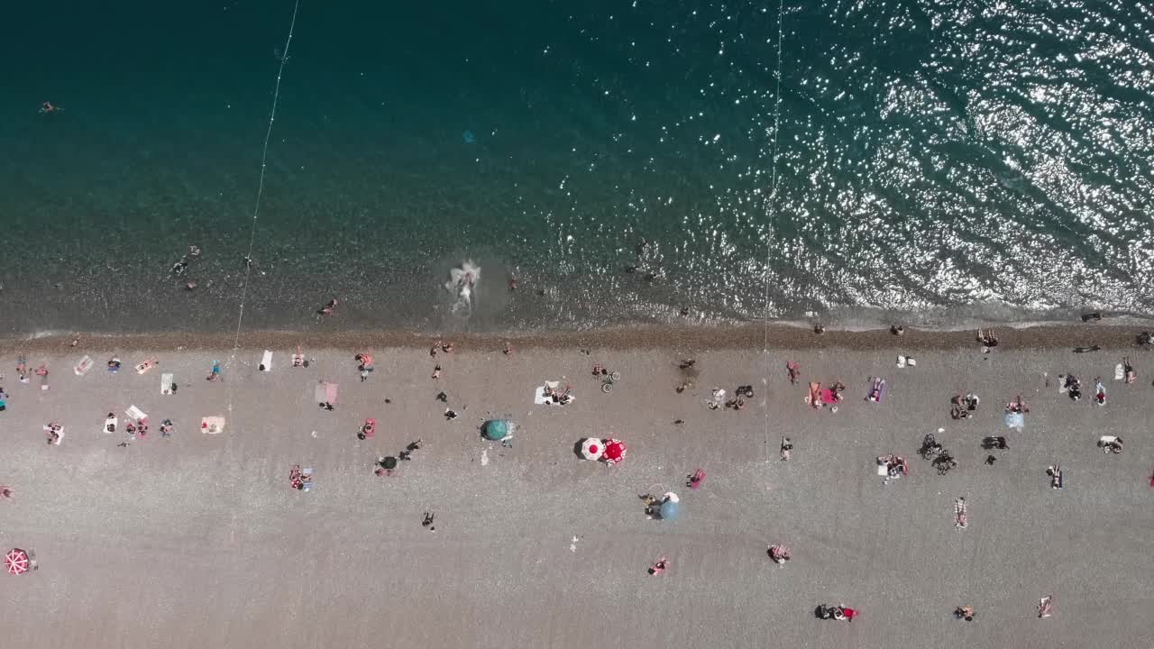 土耳其安塔利亚，有沙滩和蓝绿色海水的海滨。夏日阳光明媚的地中海海岸线。人们在海里游泳，在阳光下晒日光浴，在海滩上放松和放松视频素材