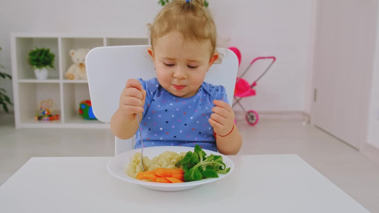 孩子吃意大利面和蔬菜。有选择性的重点。孩子。视频素材