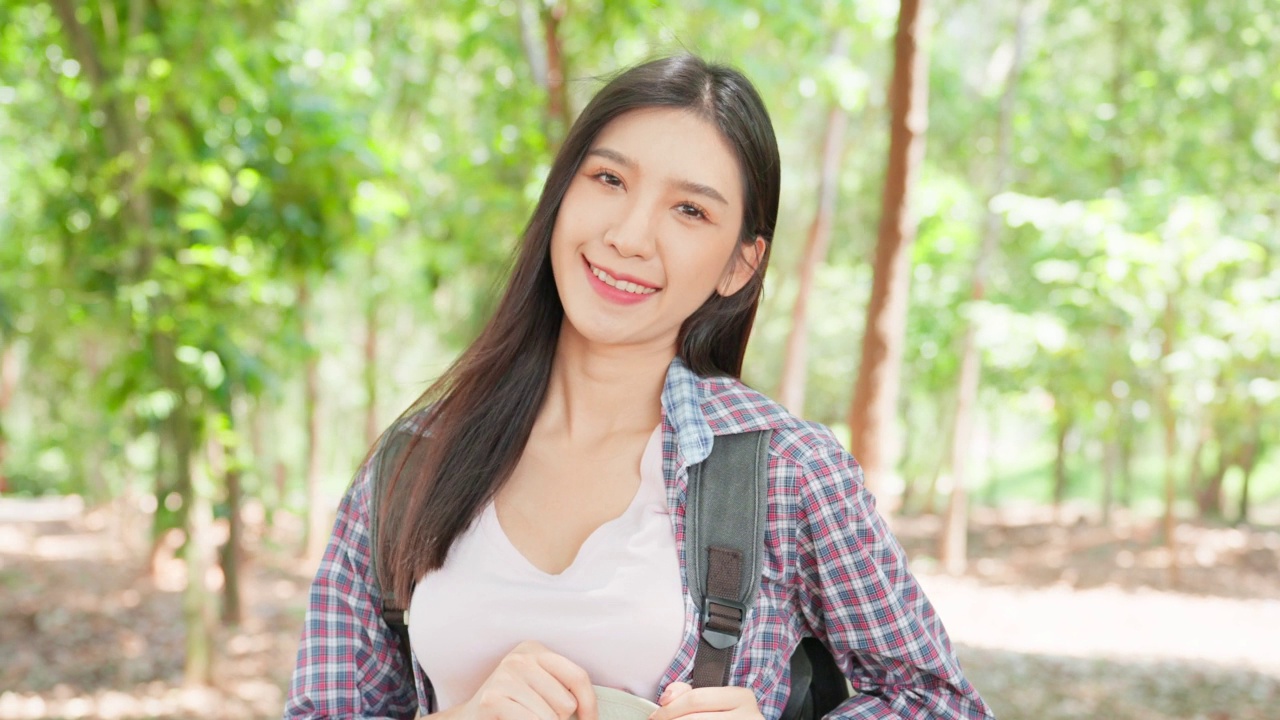 亚洲美女的肖像背包客独自在森林旅行。迷人的女孩旅行者走在自然的木材与幸福和有趣的假期旅行，然后微笑着看着相机视频素材