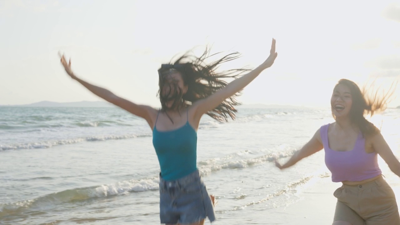 亚洲年轻美丽的女人朋友在夏天的海滩上散步。迷人的两个女孩旅行者感到快乐和放松，而在热带海岛度假旅行。视频素材