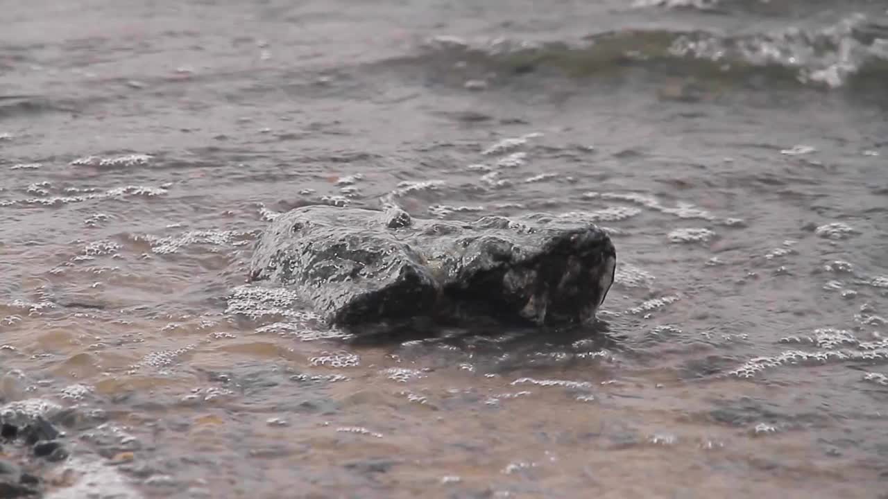 海边一块孤零零的大石头被海浪冲刷着。海岸。海浪和海岸视频素材