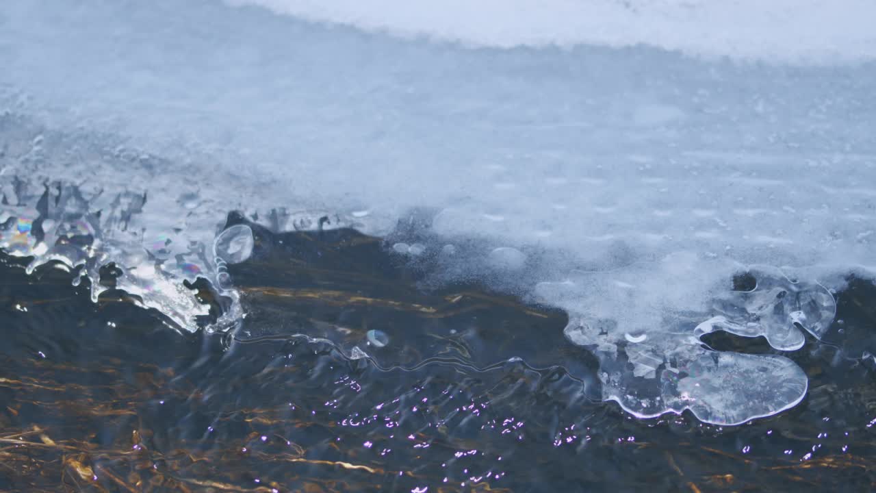 小溪从冰块中流过。早春，白天融雪。视频素材