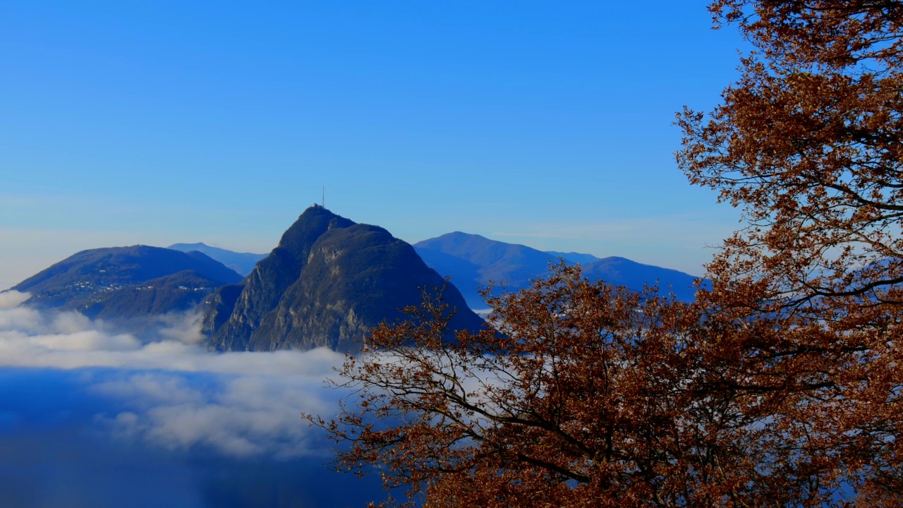 高山湖卢加诺的全景与云海和山与树在晴朗的秋日视频素材