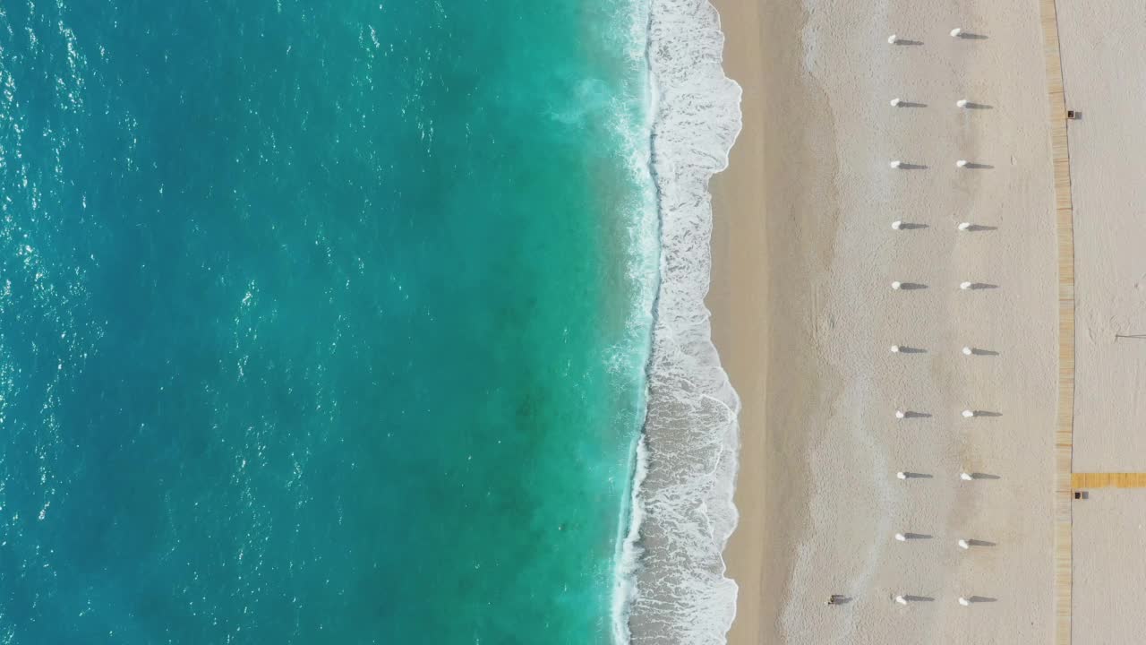 在土耳其的Oludeniz，带着遮阳伞的梦幻般的绿松石海滩鸟瞰视频素材