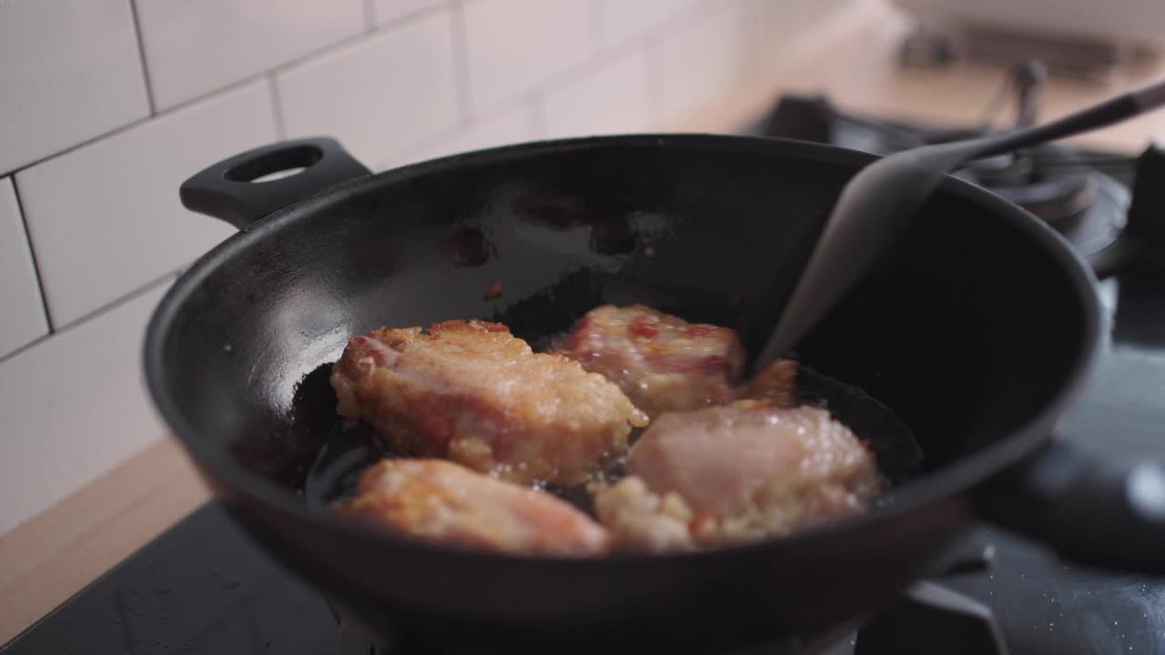 妇女手翻转猪肉烹饪亚洲食物在家庭厨房视频素材