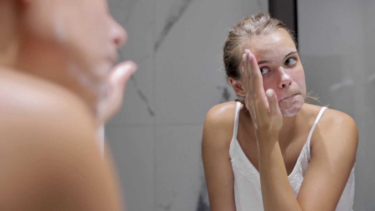 一个年轻女人在浴室里洗脸视频素材