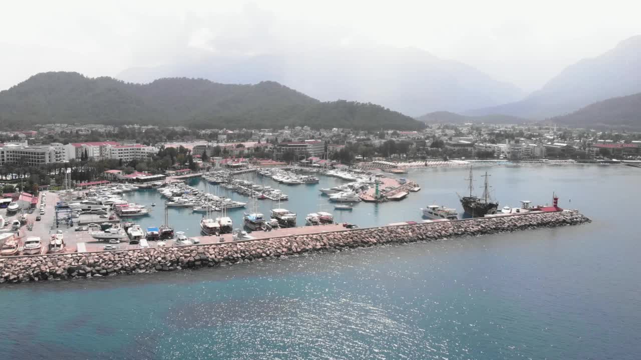 地中海海湾在土耳其安塔利亚与游艇港。船和游艇在码头附近的小旅游胜地与别墅岩石海边。港口停泊着豪华的白色游艇和快艇视频素材