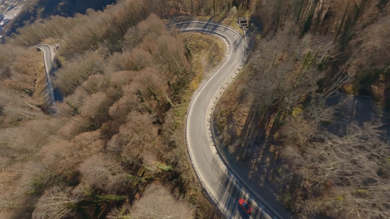 航拍极限观高档红色跑车骑在蜿蜒的公路岩石地形的山区度假村。拍摄FPV运动无人机汽车交通比赛沥青路悬崖秋天山谷4k视频素材