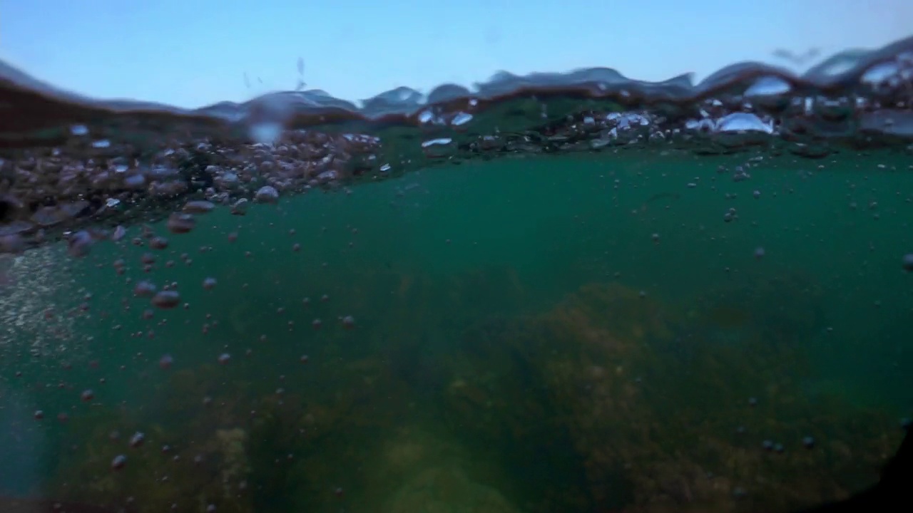 相机浸在水里，在快要淹死的大海里，在海面上。美丽的光线在水面上折射，潜水，浮潜。视频素材