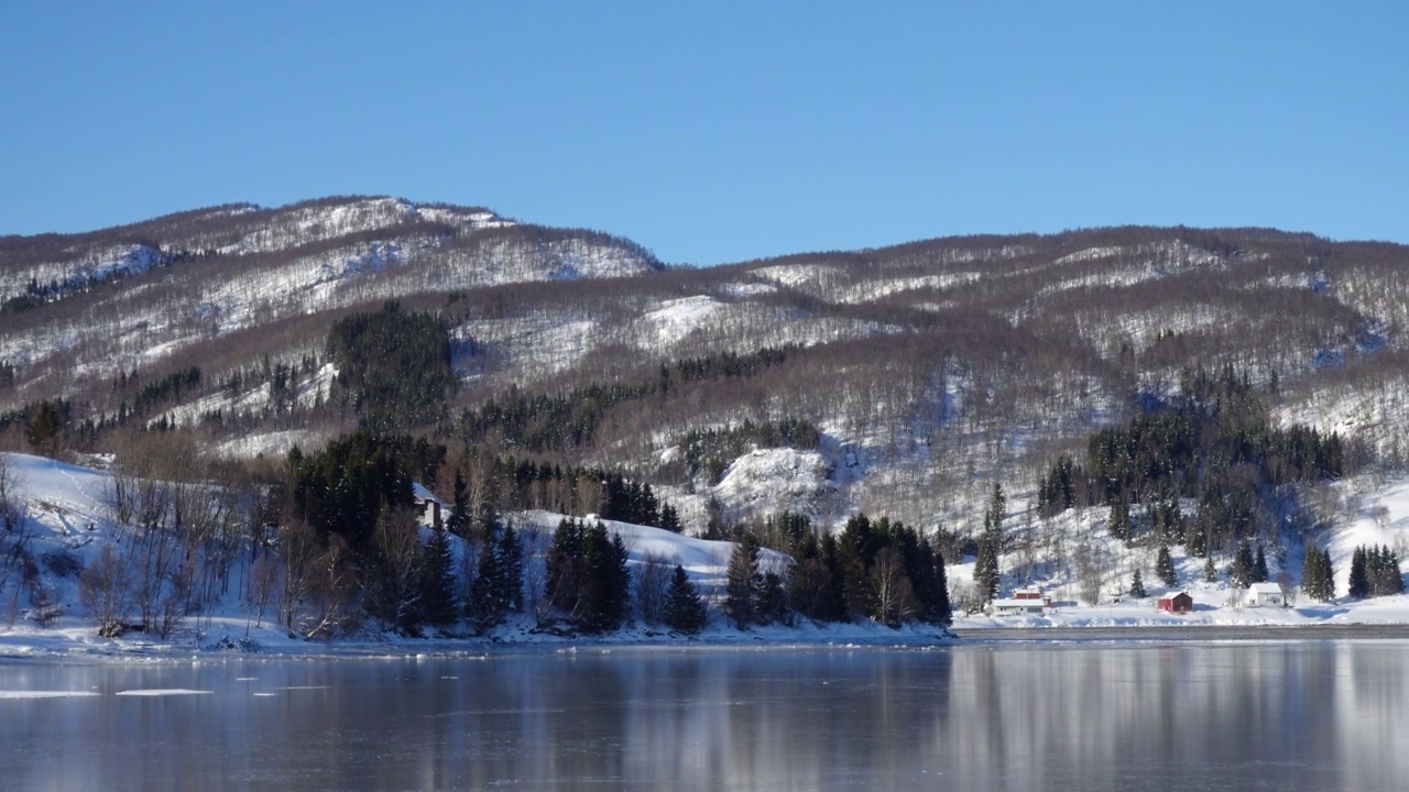 挪威冬季的全景，海边的房子和远处美丽的雪山视频素材