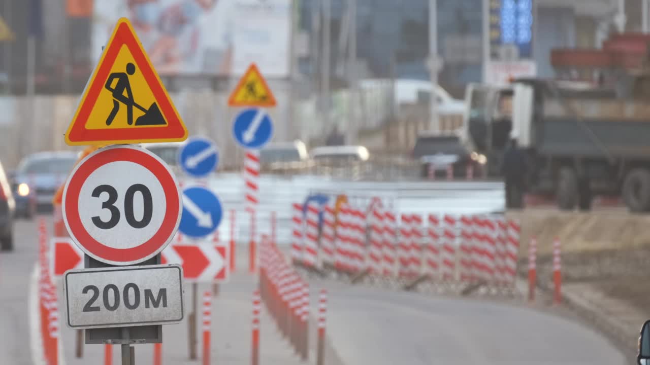 道路工程警告交通标志的建设工作在城市街道和缓慢移动的汽车视频素材