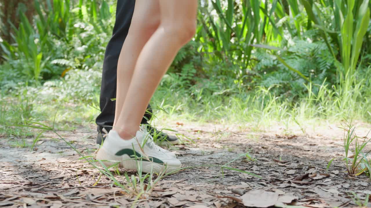 近脚的亚洲男人和女人背包客朋友一起在森林野生旅行。一对迷人的情侣在夏天的假期旅行中漫步，探索大自然的树林，幸福和乐趣视频素材