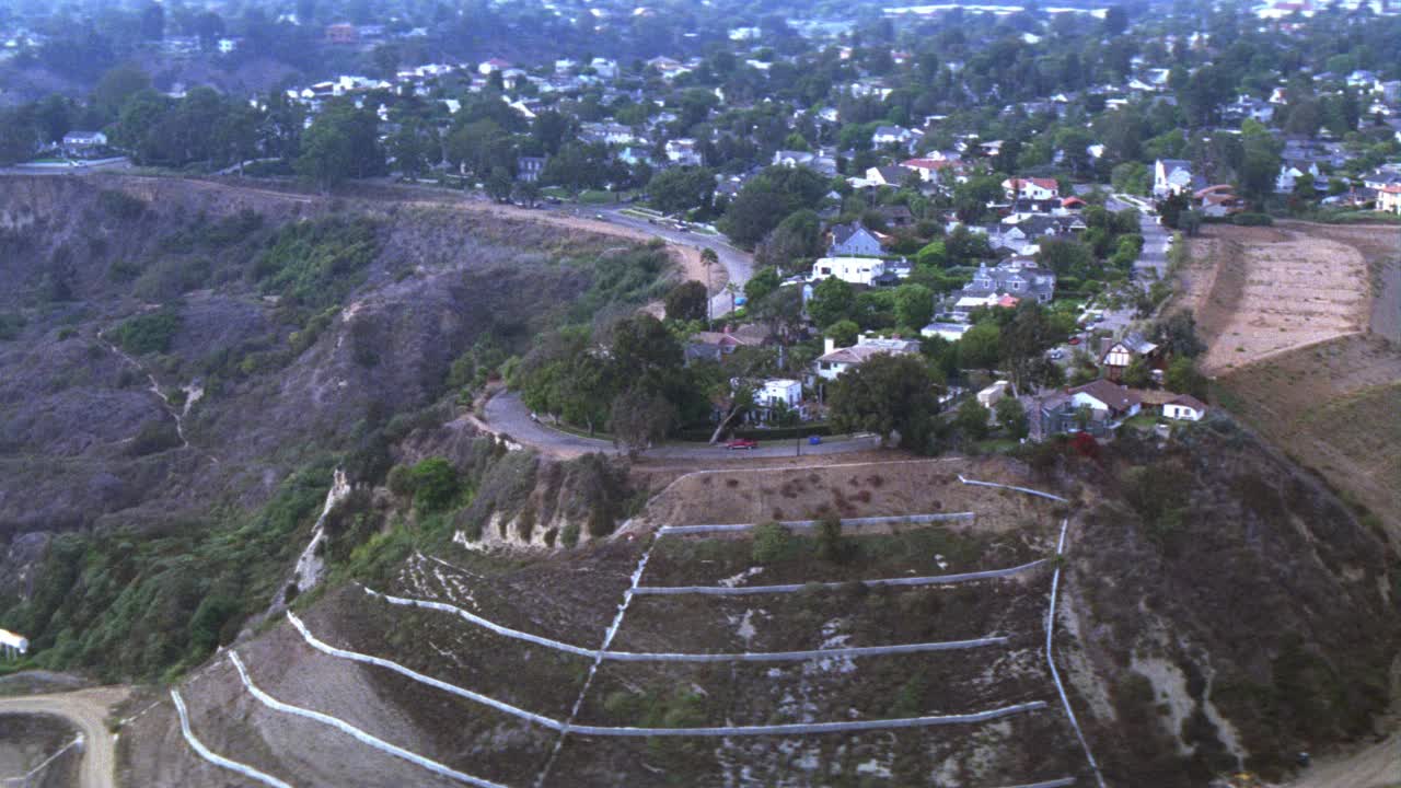 高空的上层多层房屋或大厦，和棕榈树山顶上的太平洋栅栏社区或居民区。可以看到后院有玩具的房子。山。视频素材