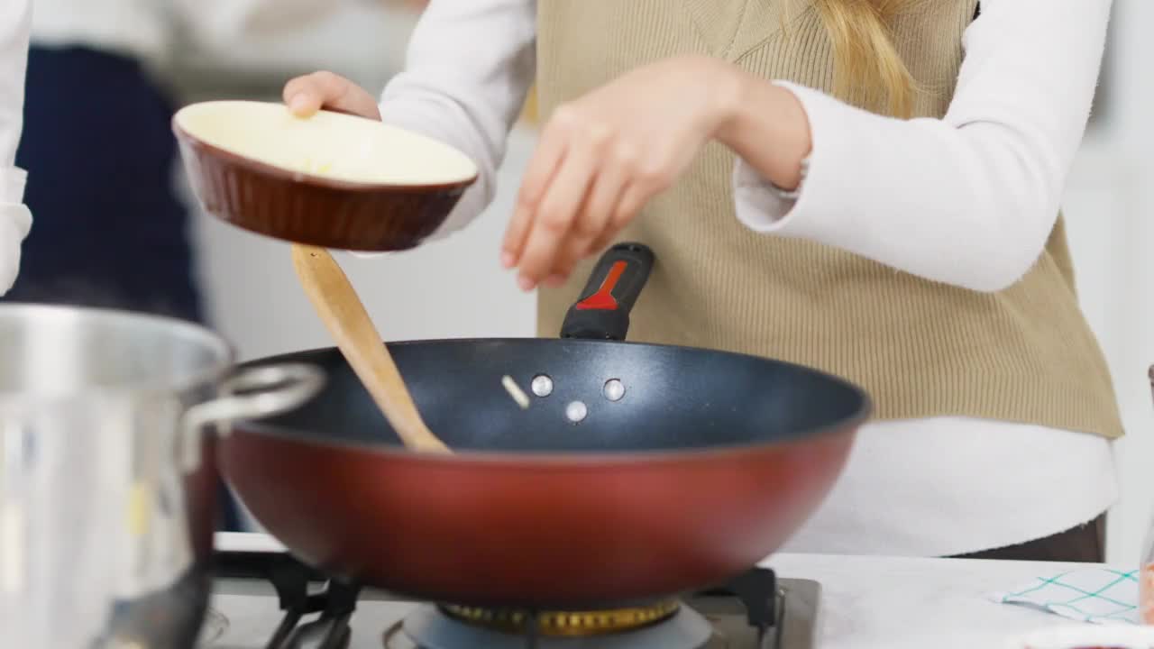 一群亚洲男女朋友在家里的厨房里一边做意大利面一边聊天。视频素材