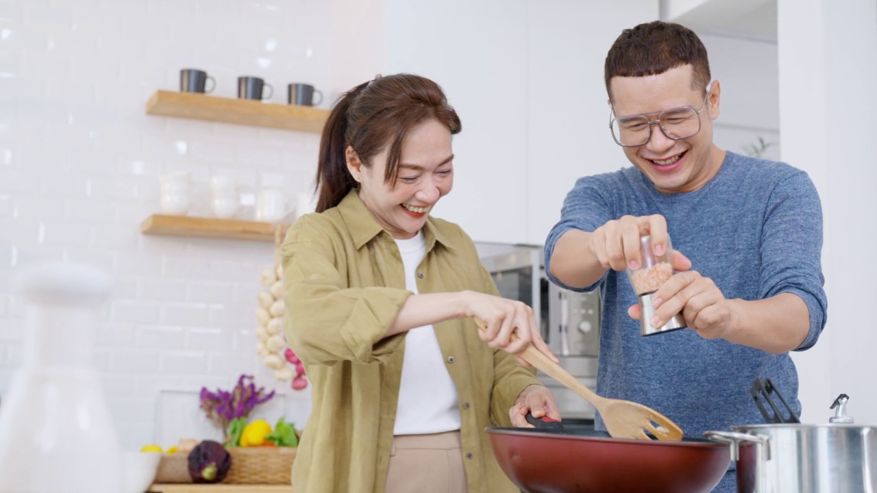 一群亚洲男女朋友在家里的厨房里一边做意大利面一边聊天。视频素材