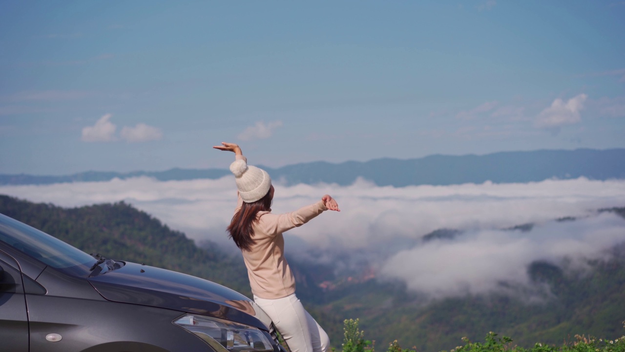 年轻女子旅行者与汽车看一个美丽的雾海在山上旅行，而驾驶公路旅行度假视频素材