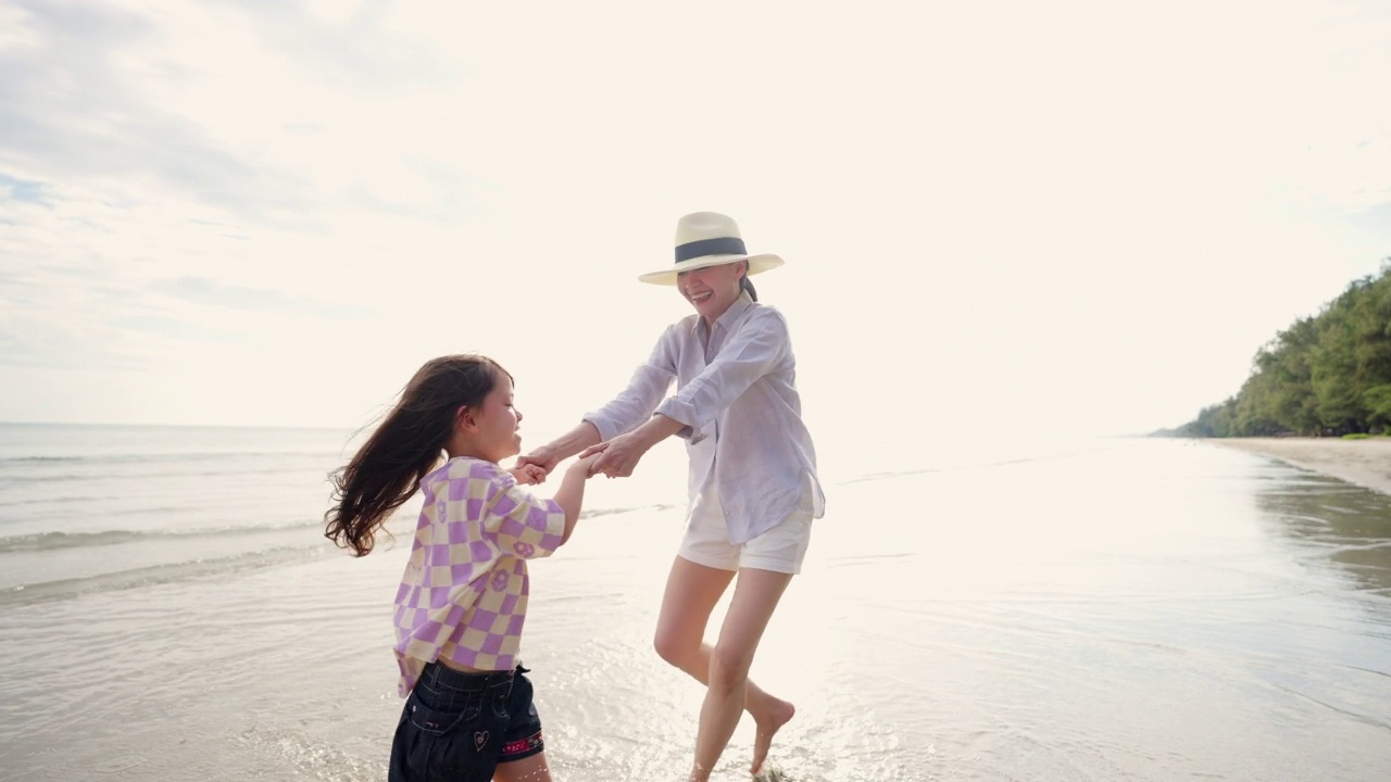 4K亚洲母亲牵着小女儿一起走在沙滩上的夏天的夕阳。视频素材