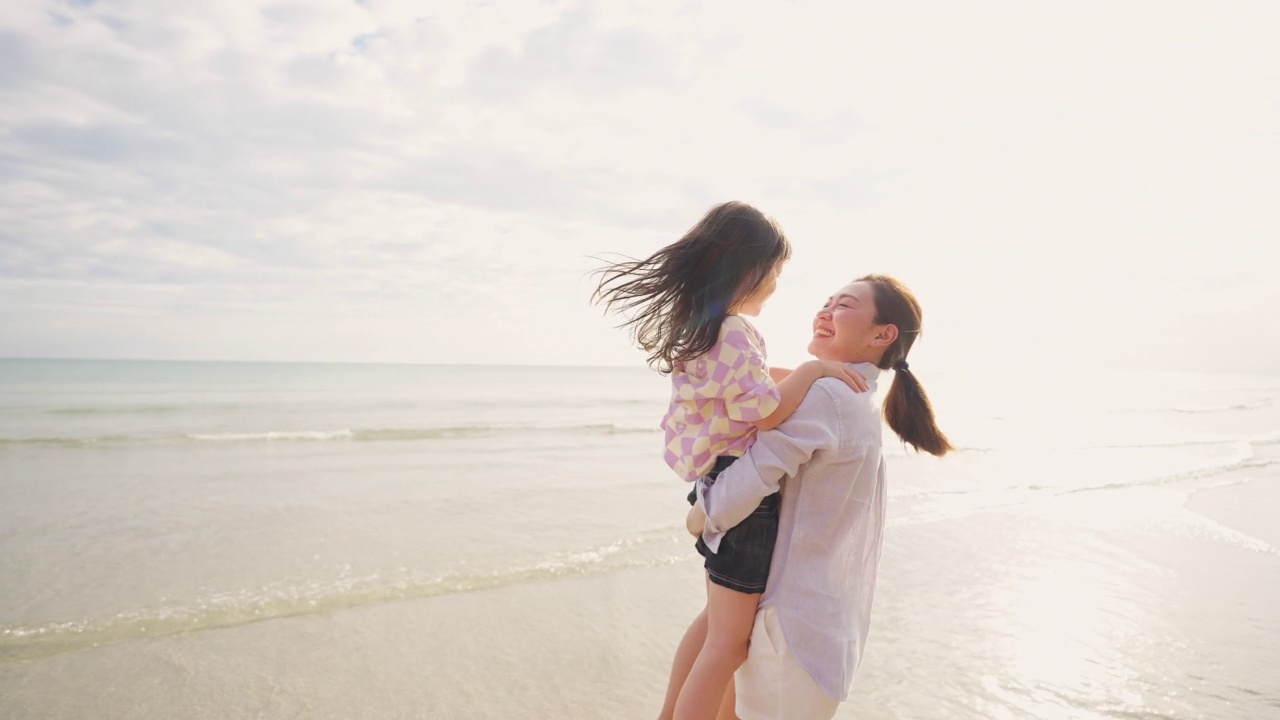 4K亚洲母亲携带和玩的小女儿在热带海滩散步在夏天的夕阳视频素材