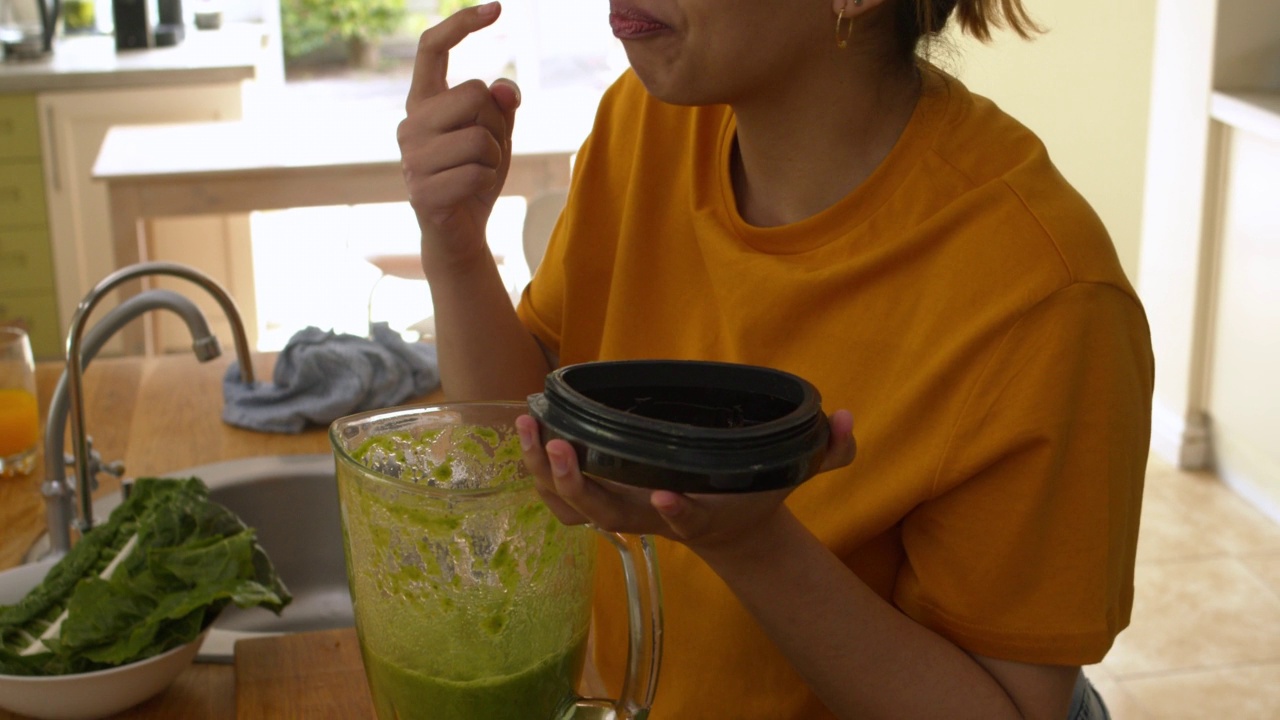 一个年轻的女人在家里做健康的饭菜。在厨房烹饪新鲜食物或做奶昔的女人视频素材