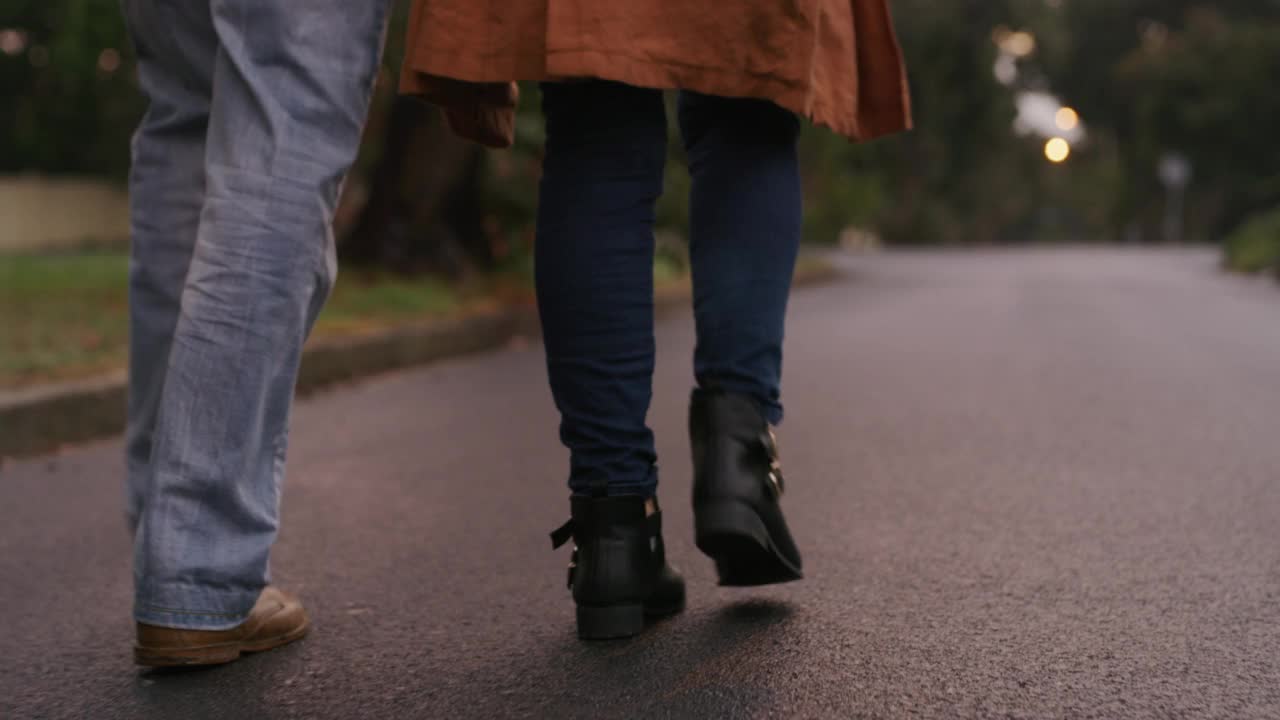 冬日里，一对面目全非的老夫妇走在街上。老年男子和妇女在户外牵手的特写镜头视频素材