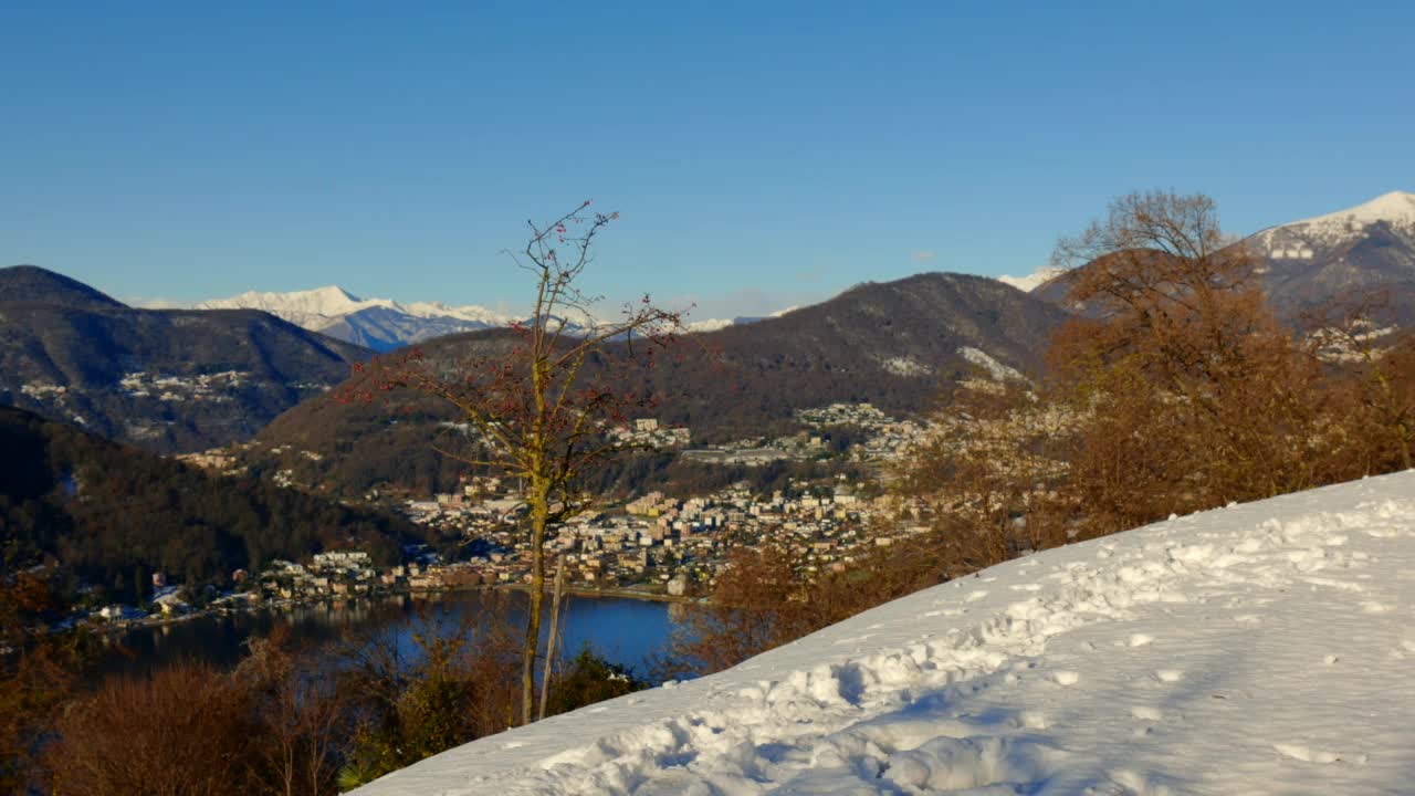 优雅的男人制造和扔雪球和欢乐的山景与卢加诺湖与雪和晴朗的蓝天在晴朗的一天视频素材