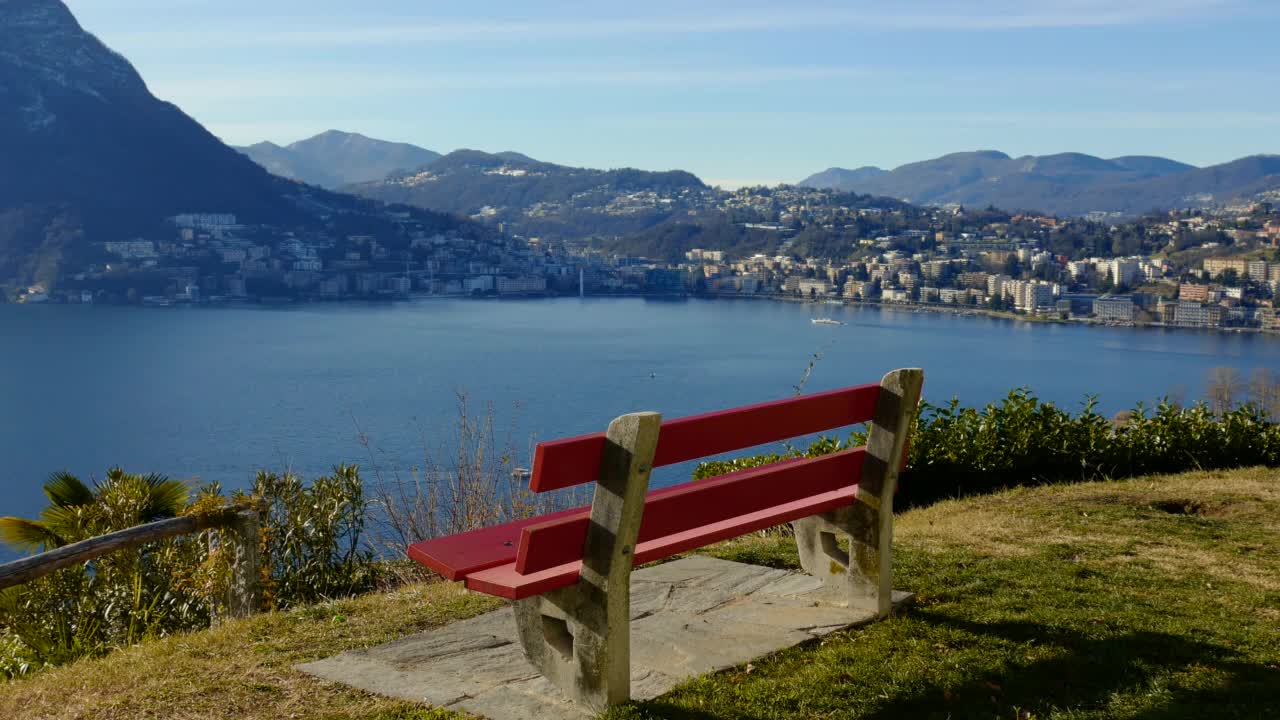 在阳光明媚的日子里，可以看到卢加诺湖的山景和卢加诺的城市风景视频素材