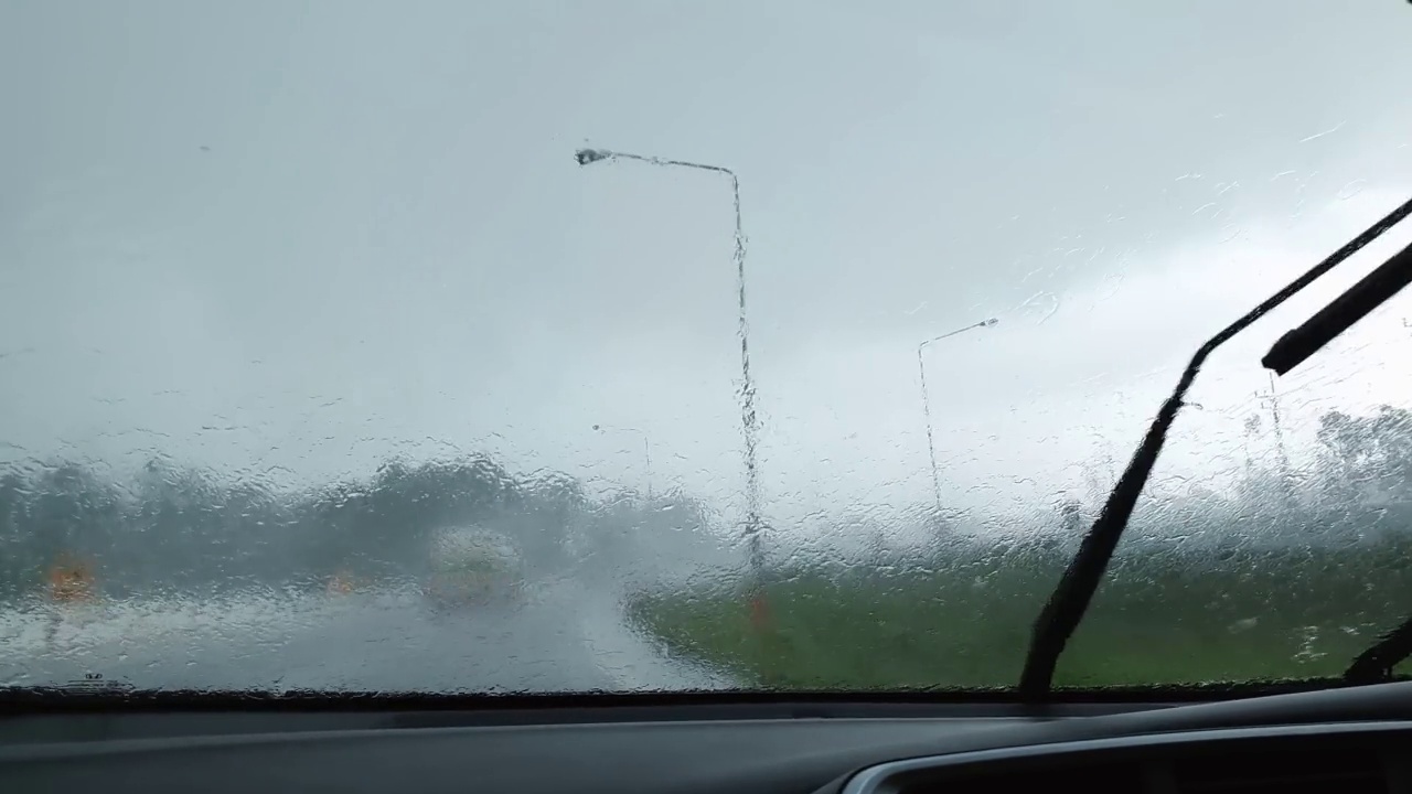 在高速公路上行驶的汽车在暴雨中可以看到雨刷在车内工作。视频素材