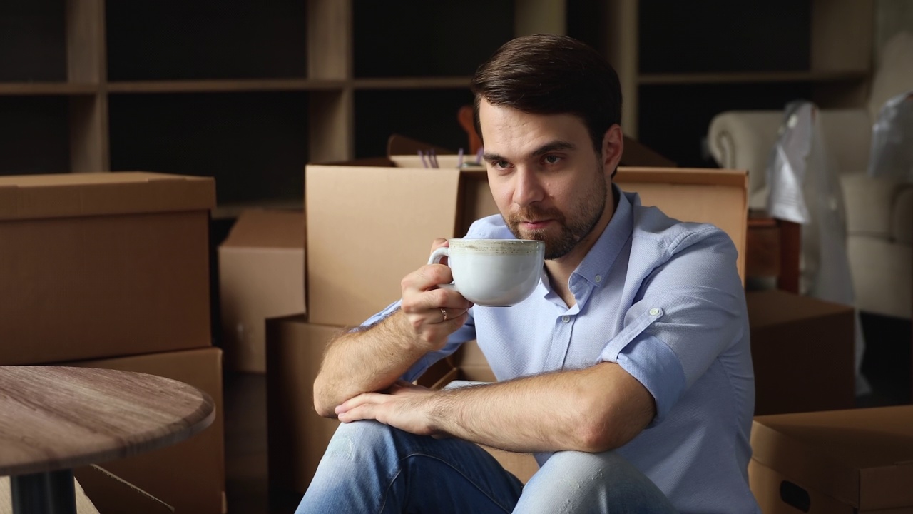 年轻单身男子在搬迁日拿着茶杯放松视频素材