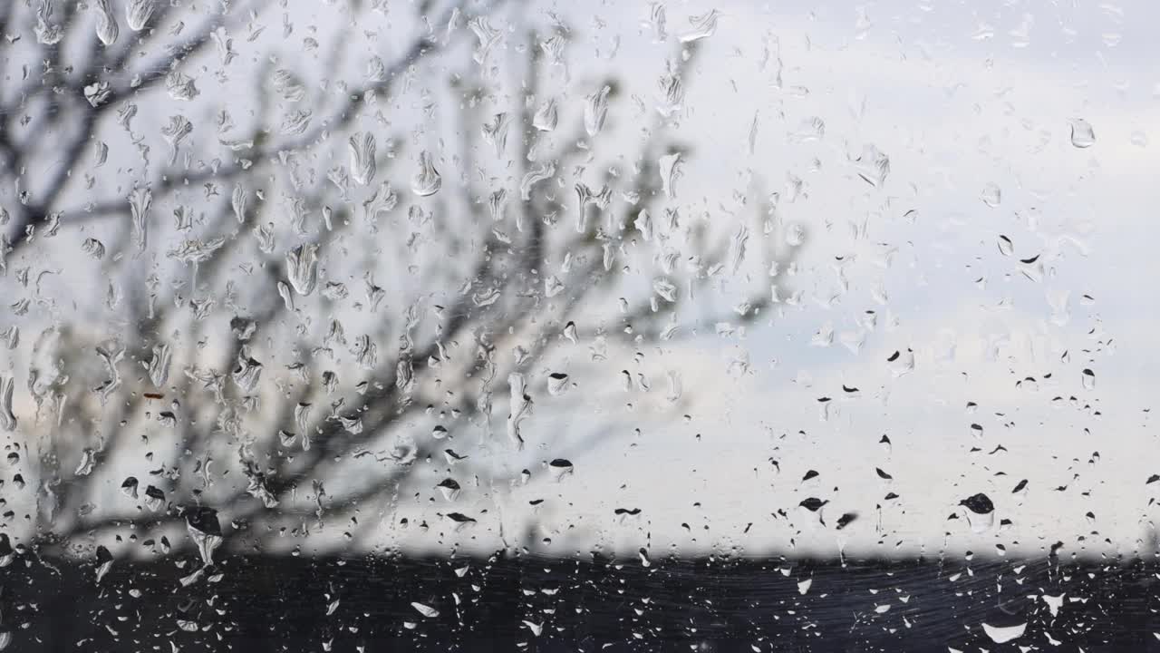 车窗玻璃被慢慢滴下来的雨滴弄湿。秋天心情难过，天气不好。视频素材