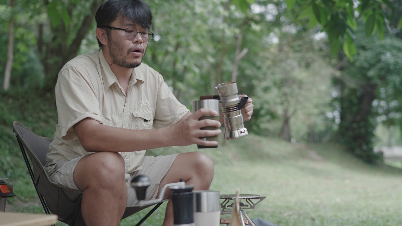 亚洲的年轻人喜欢在河边的树下做咖啡和野餐来放松自己视频素材