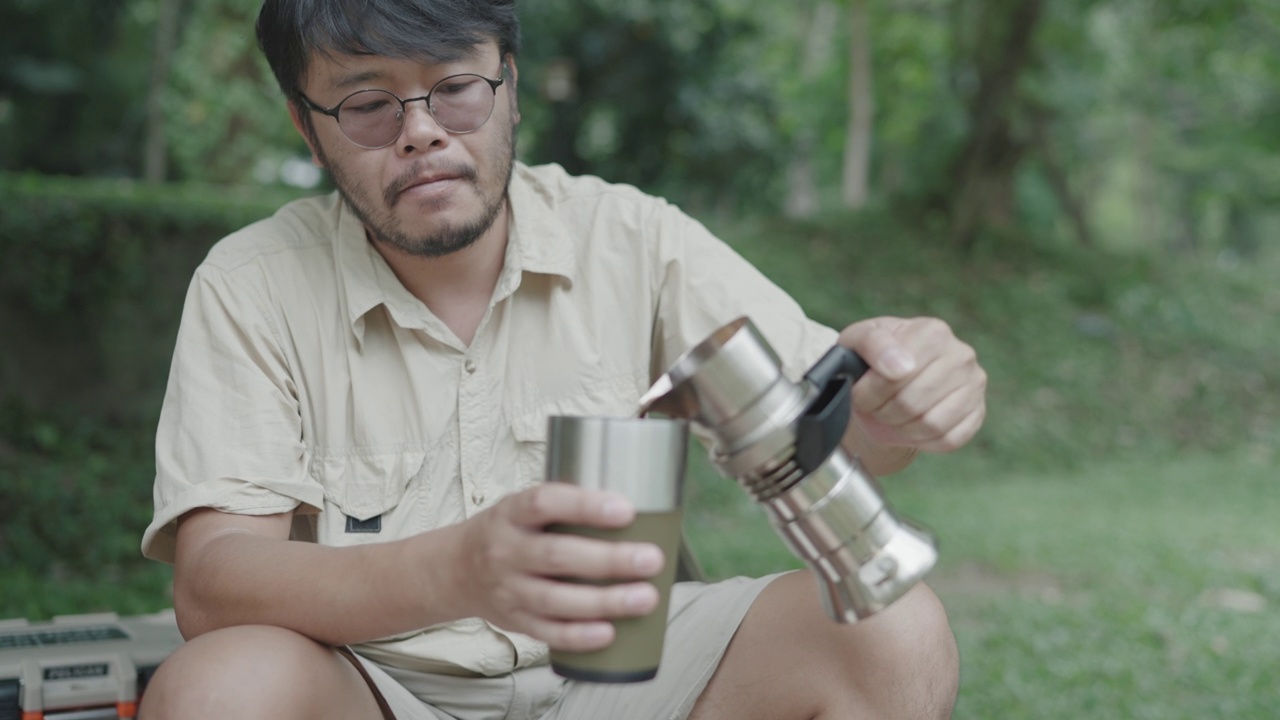 亚洲的年轻人喜欢在河边的树下做咖啡和野餐来放松自己视频素材