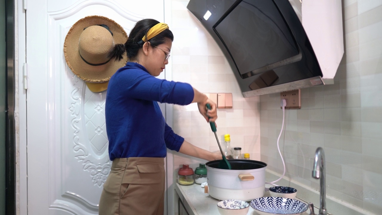 用电磁炉做饭的女人视频素材